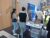 Mehrere Personen stehen an einem Infostand mit Flyern und Werbematerialien in einem modernen Innenraum bei der hobit contact.